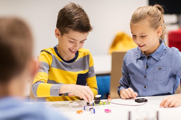 conceito de educação, crianças, tecnologia, ciência e pessoas - crianças felizes construindo robôs na aula de robótica