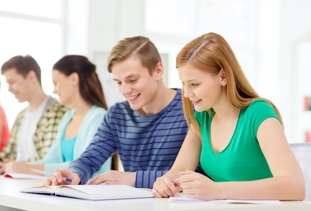 conceito de educação e escola - cinco alunos sorridentes com livros e livros na escola