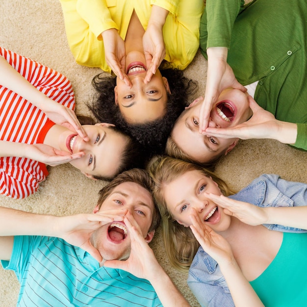 conceito de educação e felicidade - grupo de jovens sorridentes deitados no chão em círculo gritando e gritando