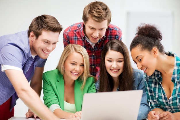 conceito de educação e internet - grupo de estudantes internacionais olhando para o laptop na escola