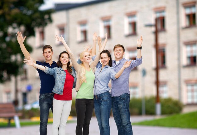 conceito de educação e pessoas - grupo de estudantes sorridentes em pé e acenando com as mãos