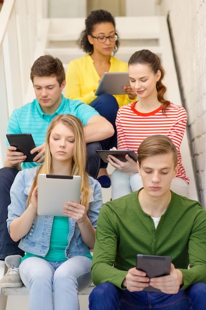 conceito de educação e tecnologia - estudantes ocupados com computador tablet pc sentado na escada
