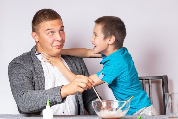 Conceito de educação e treinamento em química. Close de um menino e seu pai fazendo um experimento de química em casa e se divertindo brincando