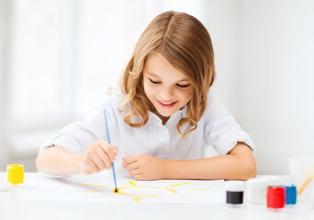 conceito de educação, escola, arte e pintura - menina aluna pintando na escola