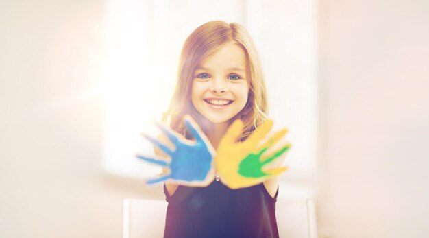 conceito de educação, escola, arte e pintura - menina estudante mostrando as mãos pintadas na escola