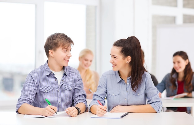 conceito de educação, escola e pessoas - dois adolescentes com cadernos olhando um para o outro na escola