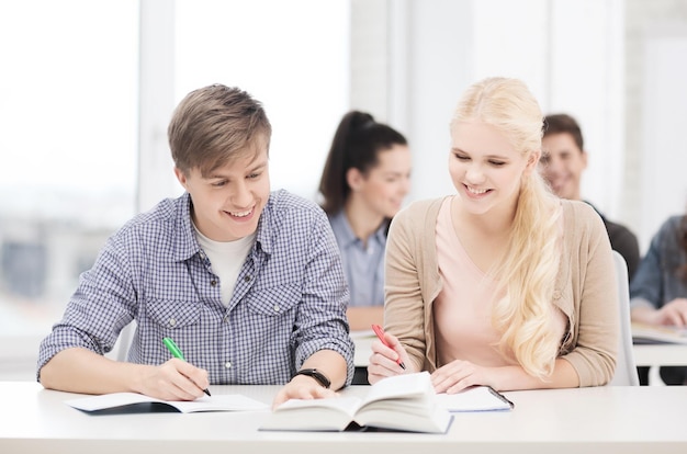 conceito de educação, escola e pessoas - dois adolescentes com notebooks e livro na escola