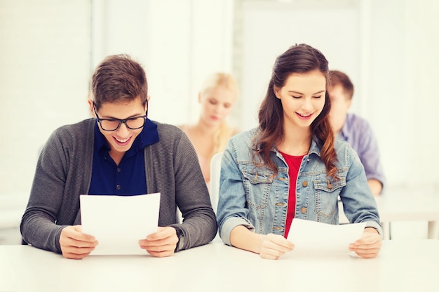 conceito de educação, escola e pessoas - dois adolescentes realizando teste ou exame com grau A