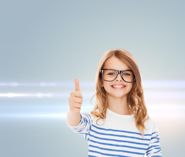 conceito de educação, escola e visão - menina bonitinha sorridente com óculos pretos mostrando os polegares para cima gesto