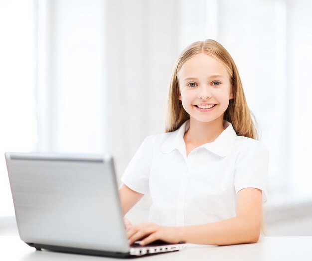 conceito de educação, escola, tecnologia e internet - menina estudante com laptop na escola