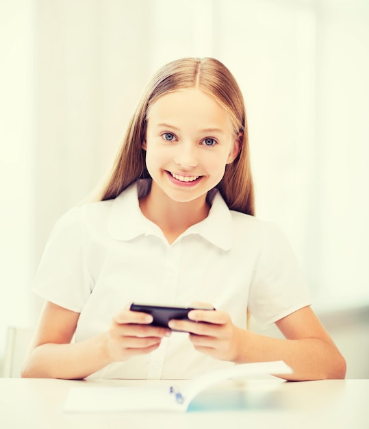 conceito de educação, escola, tecnologia e internet - menina estudante com smartphone na escola