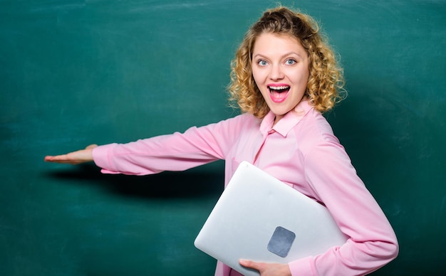 Conceito de educação escolar Palestrante explicando o tópico Mulher adorável professora segura suporte de laptop perto de quadro-negro Software para professores Educação moderna Volta às aulas Informática de ensino