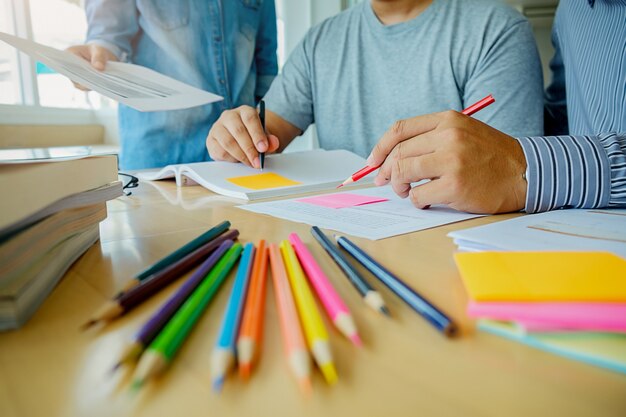 Conceito de educação. estudantes que estudam e fazem o brainstorming do conceito de campus. feche os alunos discutindo o assunto em livros de livros e escrevendo para o caderno. foco seletivo.