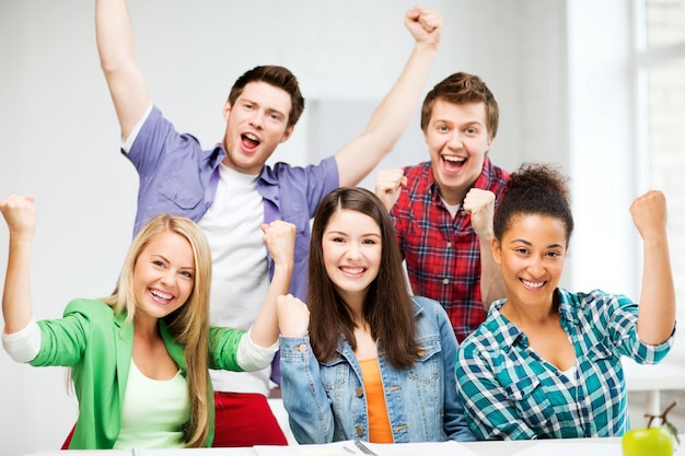 conceito de educação - feliz equipe de alunos de mãos dadas na escola