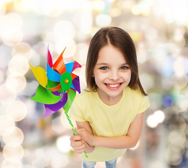 conceito de educação, infância e ecologia - criança sorridente com brinquedo colorido moinho de vento