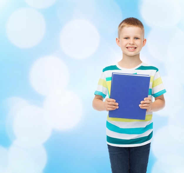 Conceito de educação, infância e escola - menino estudante sorridente com livro sobre fundo azul