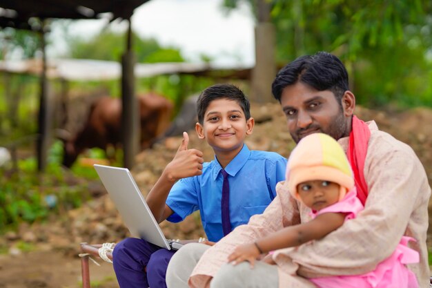 Conceito de educação: menino de escola indiano bonito usando laptop e dando algumas informações para seu pai.