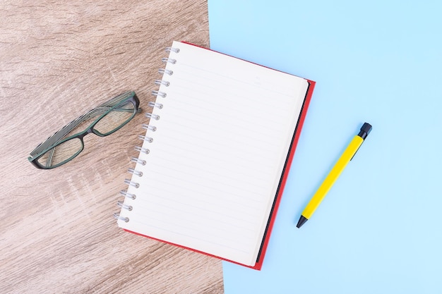 Conceito de educação ou negócios os óculos com caderno e caneta amarela colocados na mesa de madeira