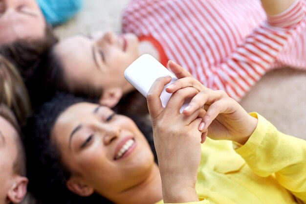 Conceito de educação, pessoas e tecnologia - close-up de estudantes ou amigos com smartphones deitados no chão em círculo