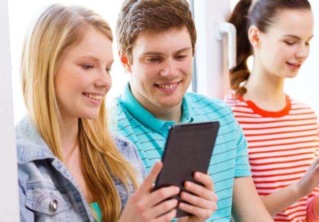 conceito de educação, tecnologia e internet - alunos sorridentes olhando para computador tablet pc na escola