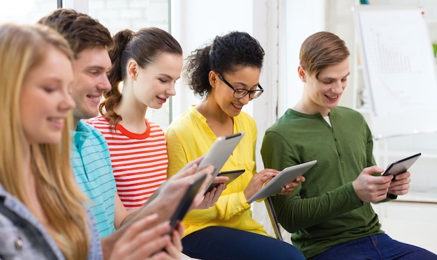 conceito de educação, tecnologia e internet - alunos sorridentes olhando para computador tablet pc na escola