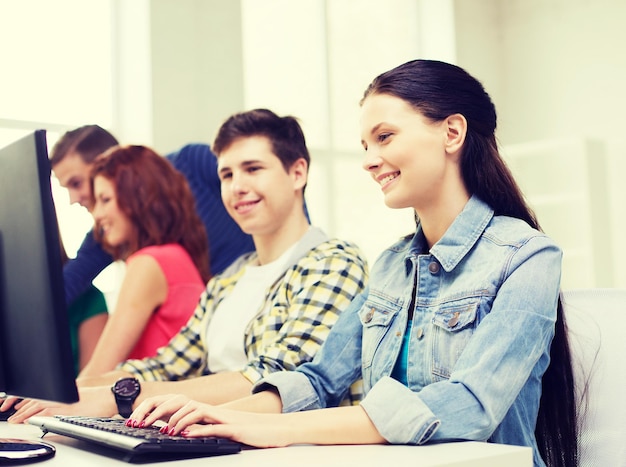 conceito de educação, tecnologia, escola e pessoas - grupo de estudantes sorridentes discutindo na aula de informática na escola