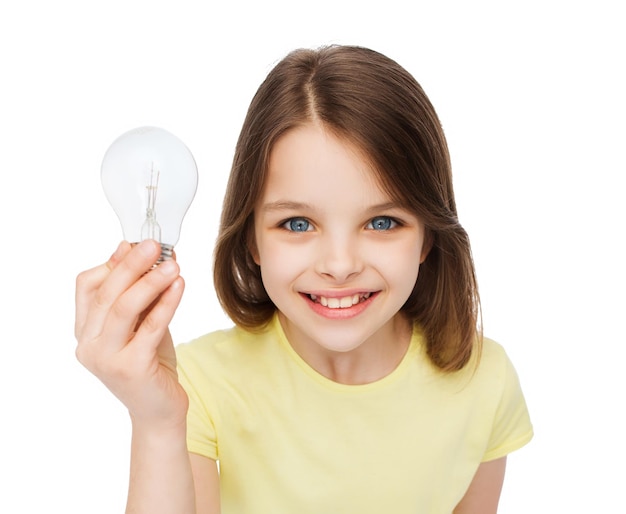 Conceito de eletricidade, educação e pessoas - menina sorridente segurando a lâmpada