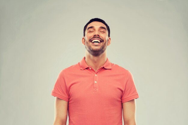 conceito de emoção e pessoas - homem rindo em camiseta polo sobre fundo cinza