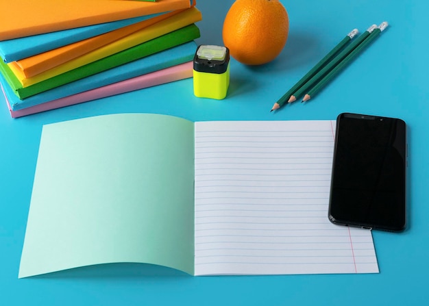 Foto conceito de ensino à distância pilha de livros caderno lápis telefone celular mesa do aluno no aprendizado on-line