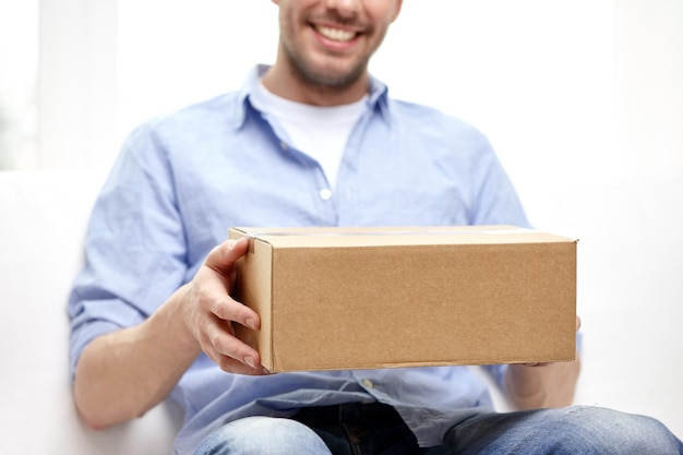 Foto conceito de entrega, correio e pessoas - homem sorridente feliz com caixa de papelão ou pacote em casa