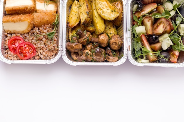 Conceito de entrega de alimentos. Batatas fritas com cogumelos, salada e trigo sarraceno em um close-up do recipiente.