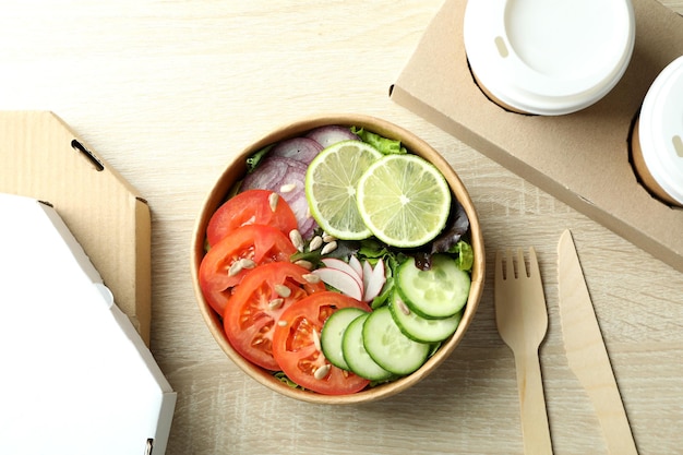 Conceito de entrega de comida com salada de legumes em fundo de madeira