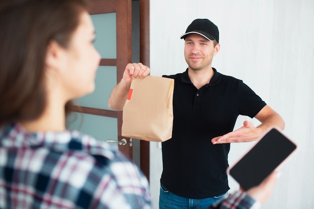 Conceito de entrega de comida. o entregador de comida trouxe comida para casa à jovem mulher.