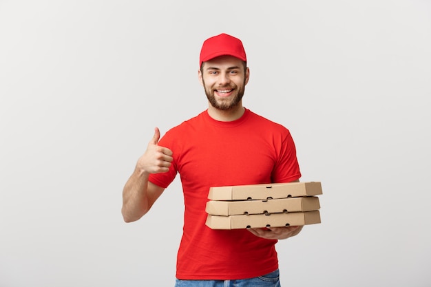 Conceito de entrega de pizza. jovem entregador bonito mostrando a caixa de pizza e segurando o polegar para cima o sinal.