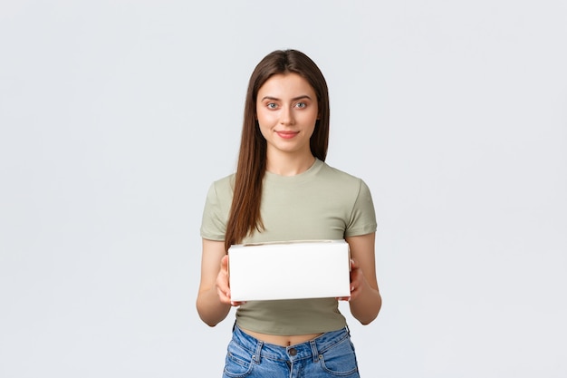 Conceito de entrega, estilo de vida e comida. Mulher bonita jovem elegante segurando a caixa com cupcakes, pedido de sobremesas do café favorito. Menina recebe entrega em casa do restaurante