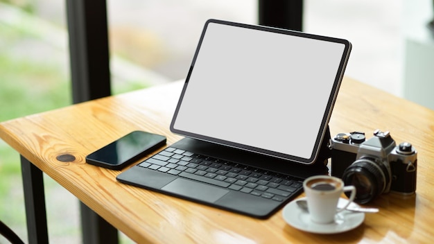 Conceito de equipamentos modernos, maquete de tela em branco de computador tablet digital moderno com smartphone, câmera e xícara de café na mesa.