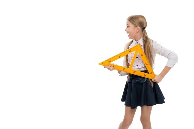 Conceito de escola Criança pequena com lição de escola de instrumento de medição Menina se preparando para aula de geometria Aluna bonita segurando régua triangular para lição se divertindo Aprecie o conhecimento