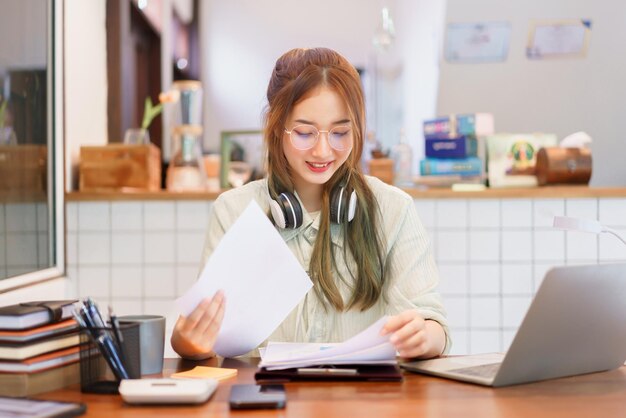 Foto conceito de escritório de espaço de coworking mulher empreendedora lendo documento de negócios e trabalhando no laptop