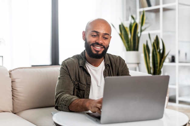 Conceito de escritório em casa Homem maduro feliz trabalhando no laptop pc sentado no sofá confortável em casa e sorrindo espaço livre