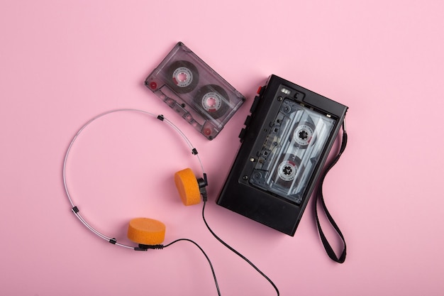 Conceito de escuta de música Leitor de áudio de fita cassete vintage e fones de ouvido fechados na vista superior de fundo rosa