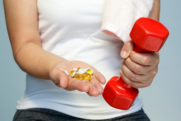 Foto conceito de esporte e dieta - mão de mulher com vitaminas e medicamentos