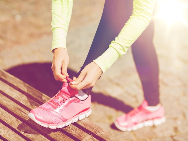 Foto conceito de esporte, fitness, exercício e estilo de vida - mulher corredor amarrando sapatos de tênis