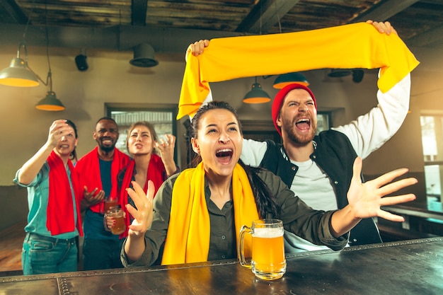 Conceito de esporte, pessoas, lazer, amizade e entretenimento - fãs de futebol felizes ou amigos do sexo masculino bebendo cerveja e comemorando a vitória em um bar ou pub