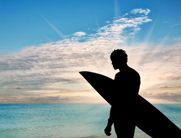 Foto conceito de esportes. silhueta de um surfista na praia ao pôr do sol no fundo do mar