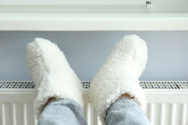Conceito de estação de aquecimento com pernas em botas de malha no radiador.