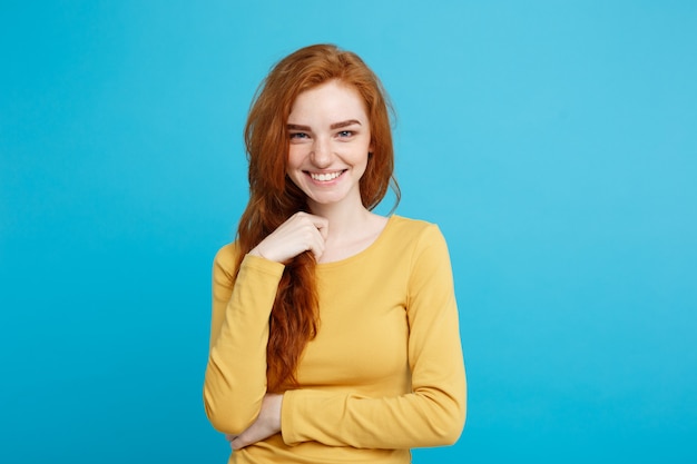 Conceito de estilo de vida, close-up, retrato, jovem, bonito, atraente, ruivo, ruivo, menina, brincando com seu cabelo com timidez, azul pastel, parede, cópia espaço