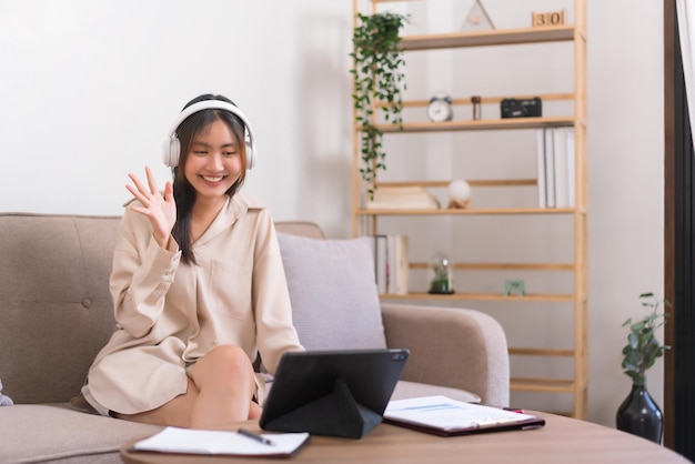 Conceito de estilo de vida de relaxamento Jovem mulher asiática fazendo gesto de saudação com amigo em videochamada