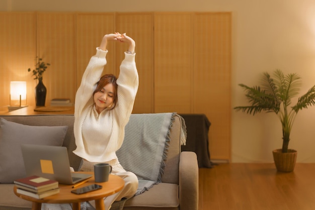 Conceito de estilo de vida doméstico Jovem mulher se esticando para relaxar depois de trabalhar duro no inverno noturno