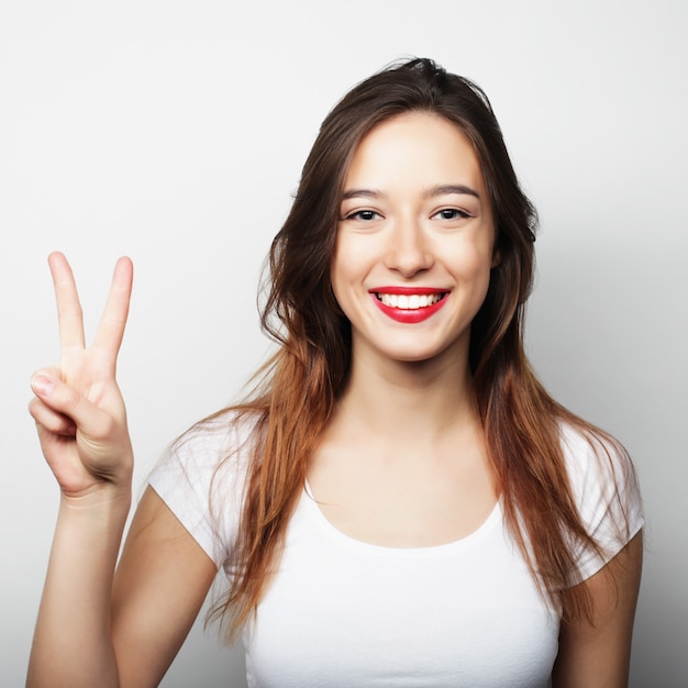 Conceito de estilo de vida e pessoas: linda mulher mostrando a vitória ou o símbolo da paz