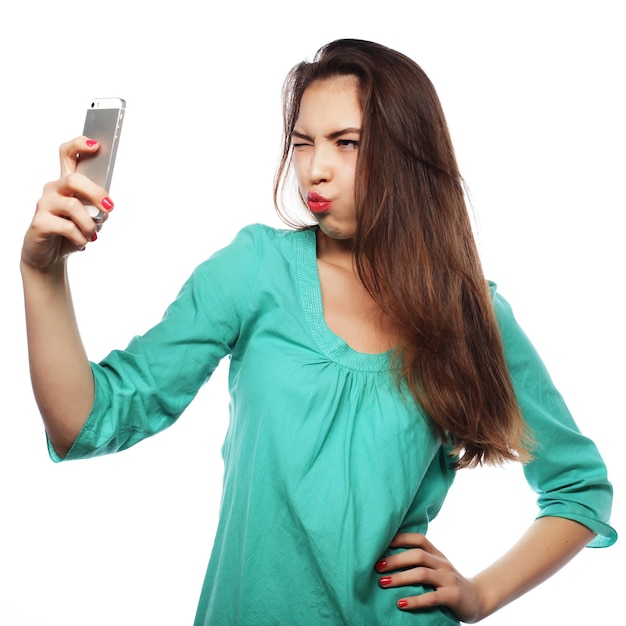 Conceito de estilo de vida e tecnologia de pessoas muito adolescente vestindo camisa verde tirando selfies com seu telefone inteligente isolado em branco